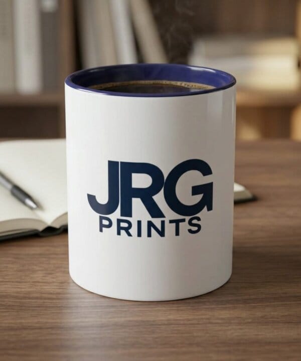 Custom branded coffee mug on a desk beside a notebook, in everyday office use